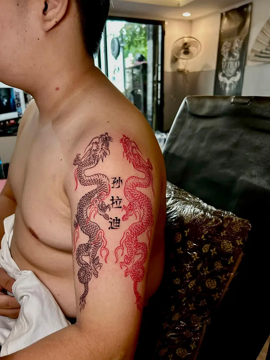 A black dragon with red ink and Chinese characters across a shoulder