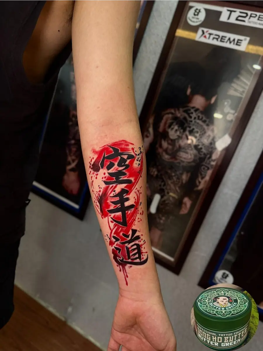 Japanese kanji brushed in red with a red sun, tattooed on a forearm