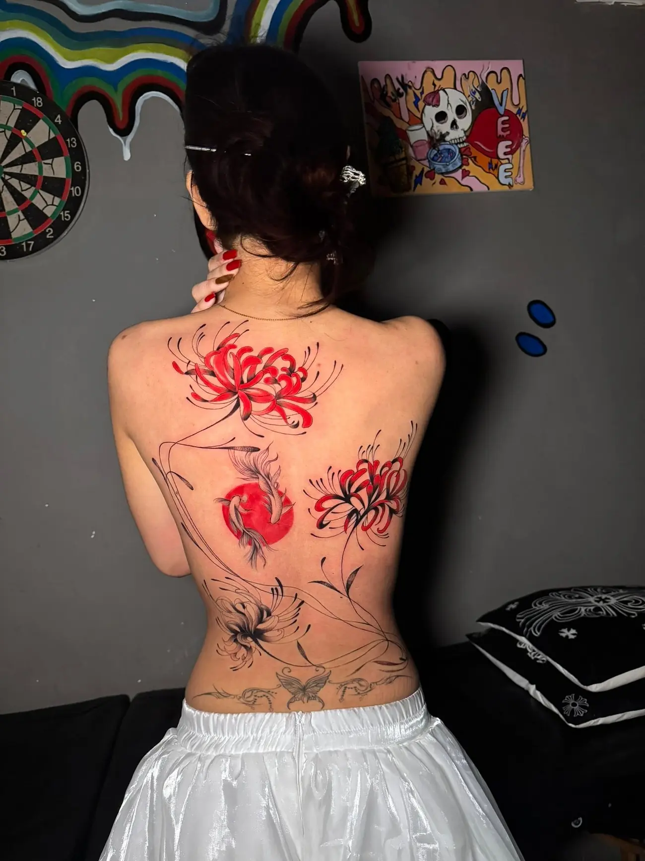 Red spider lilies with fine black linework tattooed across a client's whole back