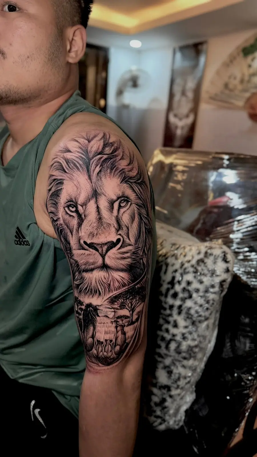 A lion portrait in black and grey on a shoulder and upper arm