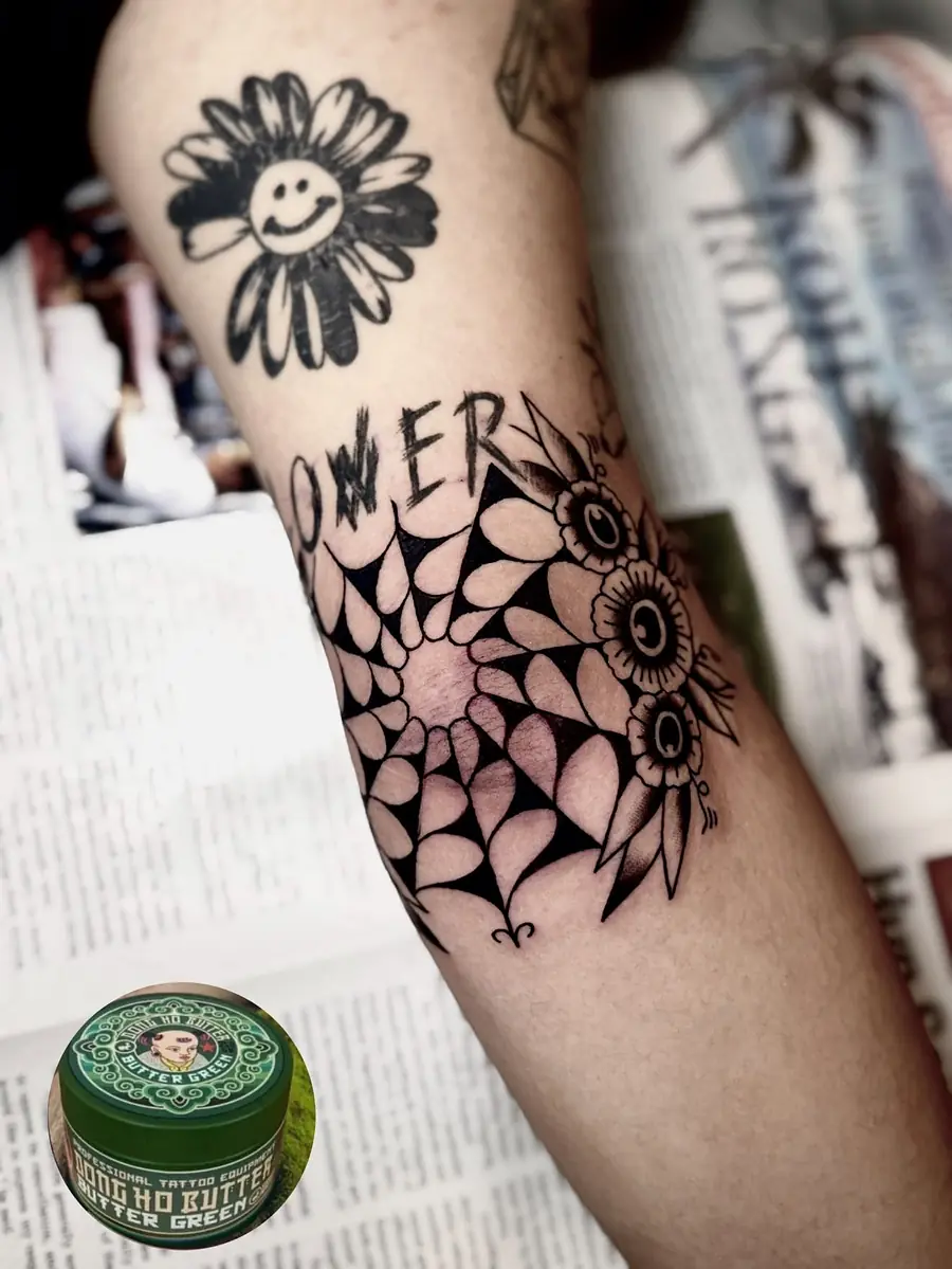 A geometric mandala wrapping the elbow with lettering above it
