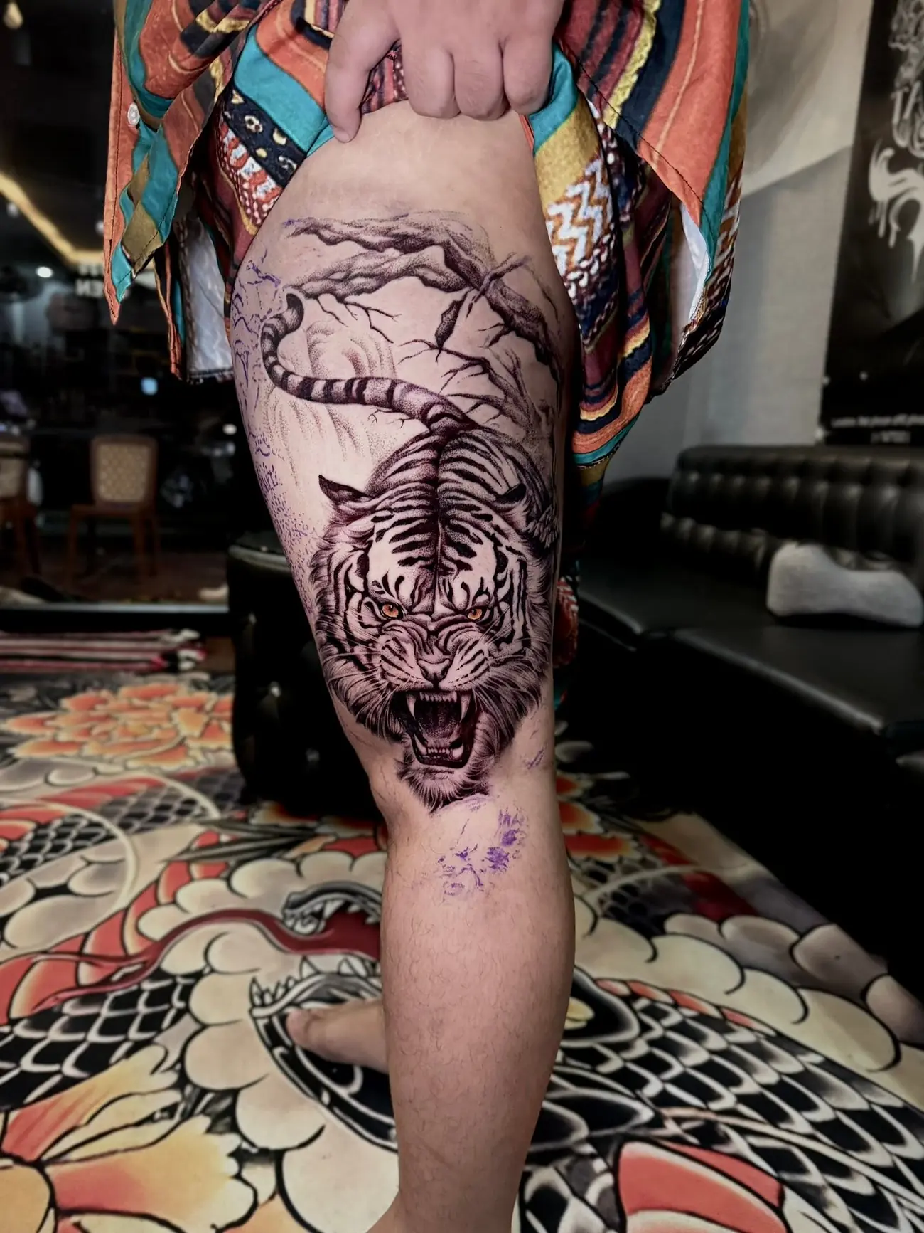 A roaring tiger in black and grey realism on a thigh